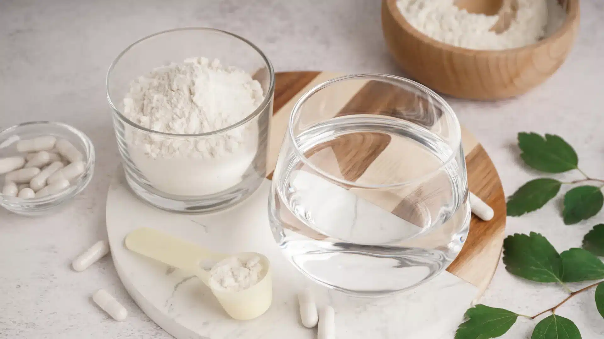 A glass of water beside a small bowl of white prescription powder on a clean kitchen counter
