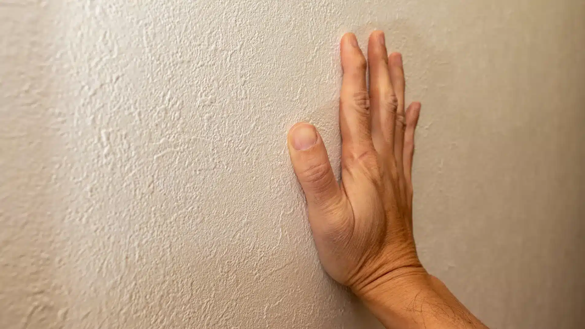 Person pressing a hand against a painted interior wall